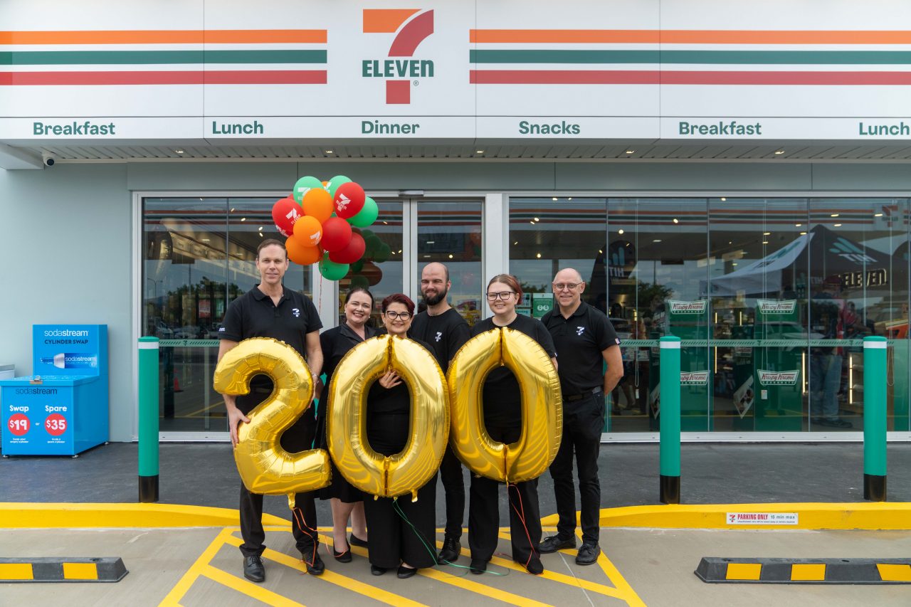 A picture of team members from 7-Eleven holding three large gold balloons that are 2-0-0