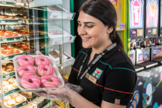 Franchisee holding a tray of iced doughnuts.