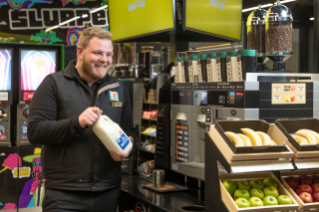 Store employee restocking milk for coffee machines.