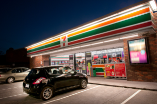 Cars parked outside a 7-Eleven store at night.