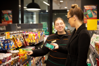 A 7-Eleven store assistant talks to a customer in-store.