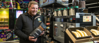 Store employee holding bag of coffee beans.