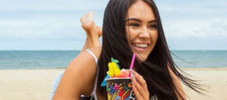 Woman drinking low sugar Slurpee on the beach.