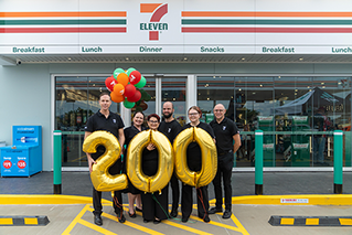 Members of the 7-Eleven team holding balloons that spell out 200