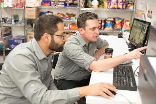 7-Eleven field team leader consulting with franchisee, they are reviewing computer reports.