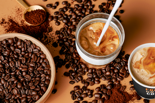 Cup of 7-Eleven coffee surrounded by coffee beans.